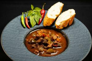 tradicional húngaro Comida carne Goulash com pão a picante pimentas foto