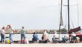 yalta 2021- pessoas pescando no aterro, barcos e iates ao fundo foto