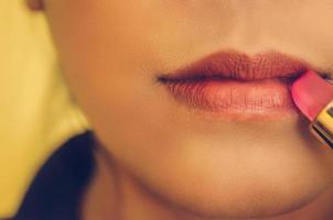 rosto de beleza de mulher aplicando batom na boca por cosméticos. foto