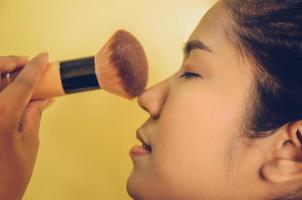 rosto de beleza de mulher asiática, aplicando pincéis na pele por cosméticos. foto