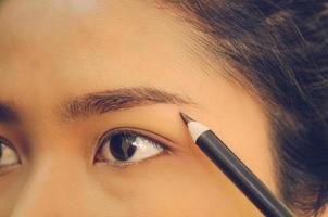 rosto de beleza de mulher asiática, aplicando o lápis de sobrancelha na pele. foto