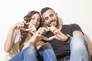 bonita jovem casal faz coração placa com dele mãos foto