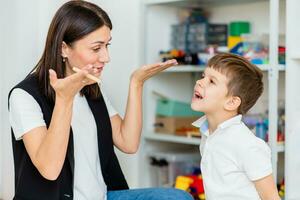 uma mulher discurso terapeuta ensina uma criança para golpe corretamente em colori penas. foto