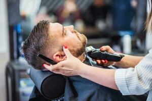 lindo cabeleireiro mulher cortes do homem barba às barbearia foto