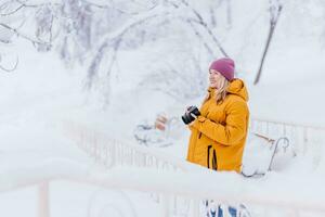 lindo menina dentro uma amarelo Jaqueta fotógrafo leva As fotos do neve dentro uma inverno parque