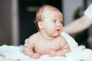 retrato do uma lindo bebê menina mentiras em uma branco Folha dentro dela quarto foto