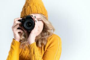 lindo menina fotógrafo dentro uma tricotado chapéu posando com uma Câmera dentro dela mãos dentro uma foto estúdio