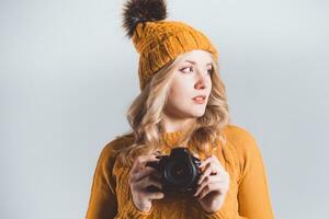 lindo menina fotógrafo dentro uma tricotado chapéu posando com uma Câmera dentro dela mãos dentro uma foto estúdio