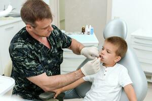 ortodontista Verificações a criança dentes dentro a clínica foto