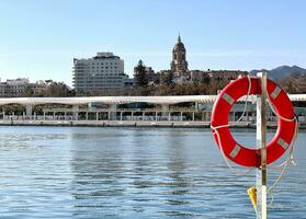 ensolarado dia dentro a Porto do málaga com Visão do a velho cidade, costa del Sol, sulista Andaluzia, Espanha. bóia salva-vidas mar Visão málaga porto. foto