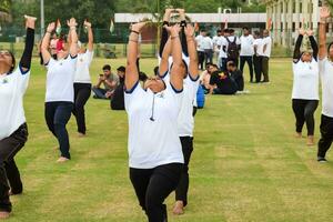 Novo Délhi, Índia, Junho 21, 2023 - grupo ioga exercício sessão para pessoas às yamuna Esportes complexo dentro Délhi em internacional ioga dia, grande grupo do adultos atendendo ioga classe dentro Grilo estádio foto