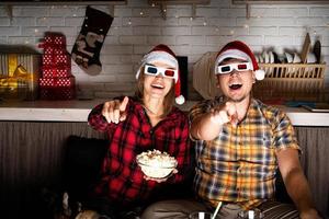 jovem casal em óculos 3D assistindo filmes em casa no natal foto