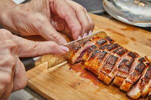 chefe de cozinha fatias a acabado Pato seio depois de fritar em de madeira borda para servindo foto