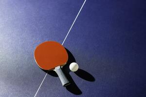 mesa tênis raquete em a azul ping pong mesa foto