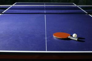 mesa tênis raquete em a azul ping pong mesa foto