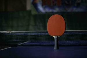 mesa tênis raquete em a azul ping pong mesa foto