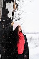 retrato de uma jovem sorridente ao lado de uma árvore na neve foto