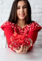 mulher de vestido vermelho segurando um presente para o dia dos namorados foto