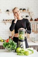 mulher fazendo smoothie verde na cozinha de casa foto