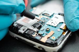 técnico que repara o interior do telefone móvel com o ferro de solda. foto
