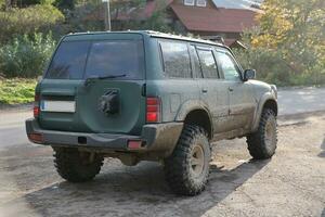 automóvel dentro uma campo panorama com uma lama estrada. fora da estrada 4x4 suv automóvel com sujar corpo depois de dirigir dentro turvar estrada foto