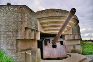 uma ampla canhão é sentado dentro a meio do uma concreto bunker foto