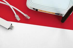 Mônaco bandeira retratado em mesa com Internet rj45 cabo, sem fio USB Wi-fi adaptador e roteador. Internet conexão conceito foto