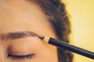 rosto de beleza de mulher asiática, aplicando o lápis de sobrancelha na pele.