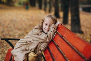 uma menina em um vestido amarelo e um casaco bege caminha no parque outono foto