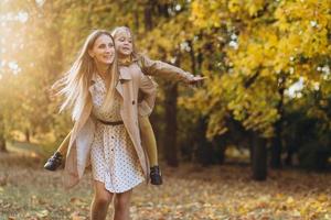 mãe e filha se divertem e caminham no parque outono. foto