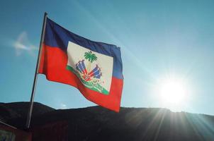 bandeira haitiana soprada pela brisa com um pôr do sol lançando raios de luz foto