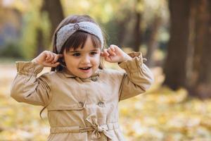 linda garota fecha os ouvidos com os dedos no parque de outono foto