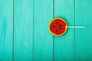 alimentos doces de verão melancia sobre fundo azul de madeira. vista do topo. brincar. copie o espaço. doce pirulito foto