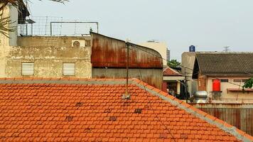 Visão do a cobertura do a velho casa e a azul céu. a Castanho telha cobertura dentro suburbano área dentro Jacarta foto