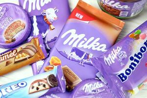 kharkov, ucrânia - 2 de julho de 2021 produtos de chocolate milka com design clássico de embrulho de cor lilás na mesa branca foto