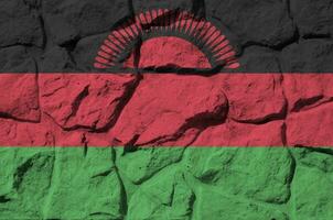 malawi bandeira retratado dentro pintura cores em velho pedra parede fechar-se. texturizado bandeira em Rocha parede fundo foto