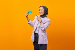 mulher asiática sorridente mostra cartão de crédito a gesticular com o dedo