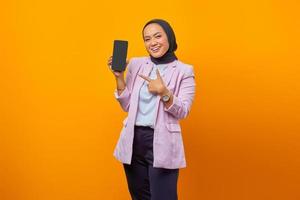 jovem mulher asiática apontando alegremente no smartphone com o dedo foto
