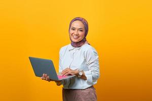 retrato de uma mulher asiática sorridente segurando um laptop e olhando para a câmera foto