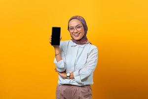 mulher asiática alegre mostrando a tela em branco do smartphone foto