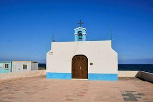 uma pequeno capela com uma azul porta e uma Cruz em topo foto