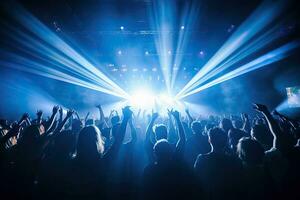 multidão às show com elevado mãos dentro frente do brilhante etapa luzes, noite clube debaixo azul raios viga e jovem pessoas segurando luz desfrutando às show conceito, ai gêneros foto