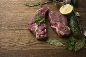 Bifes de carne crua e suculenta prontos para assar em um fundo de madeira foto