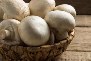 cogumelos champignon em uma cesta de vime em um fundo de madeira foto