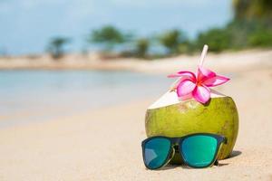 coco e óculos de sol na praia tropical. foto