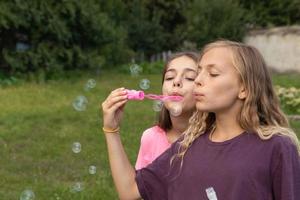 duas meninas soprando bolhas de sabão - tempo despreocupado e divertido e amizade foto