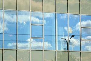 vidro construção com transparente fachada do a construção e azul céu. estrutural vidro parede refletindo azul céu. abstrato moderno arquitetura fragmento. contemporâneo arquitetônico fundo. foto