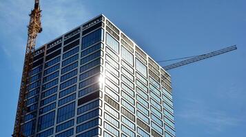 vidro construção com transparente fachada do a construção e azul céu. estrutural vidro parede refletindo azul céu. abstrato moderno arquitetura fragmento. contemporâneo arquitetônico fundo. foto