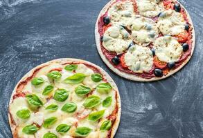 dois pizzas com ingredientes em a de madeira fundo foto