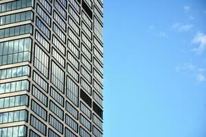 moderno escritório construção com vidro fachada em uma Claro céu fundo. transparente vidro parede do escritório prédio. foto